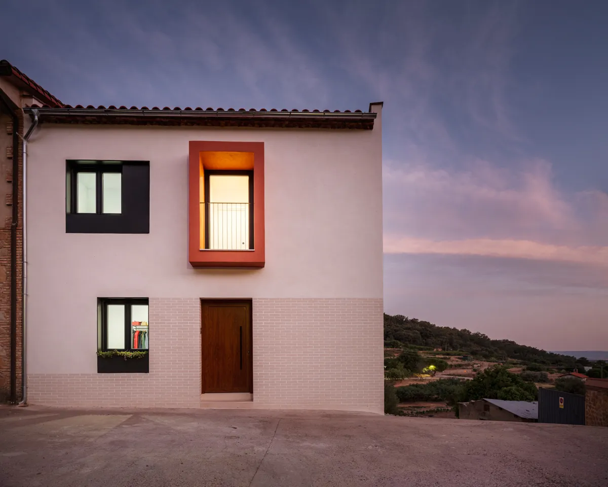 Fachada principal de la vivienda al caer la tarde en La Vera, proyecto de Nuba Arquitectura